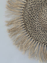 Woven placemat with fringe detail on a light gray background