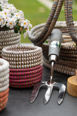 Metal garden tool with a hose and flower pots on a table