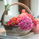 Woven basket with pink flowers on a light surface