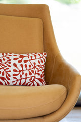 Brown chair with a red and white patterned pillow