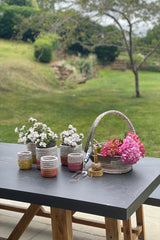 Decorative wicker baskets and flower pots on a table outdoors with a garden background