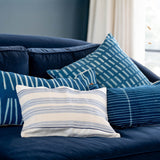 Blue and white patterned pillows on a navy blue sofa in a living room setting.