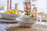 Dining table setting with woven bowl, lemons, and glasses.