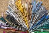 Assorted colorful tassels arranged in a circular pattern on a textured surface.