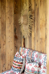 Decorative broom with a decorative pillow against a wooden wall