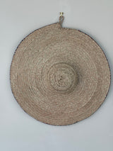 Round woven mat with concentric circle pattern on a gray background