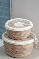 Two woven baskets with white lids on a neutral background