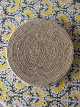 Round woven placemat on a patterned fabric background