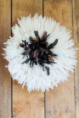 White feathered wreath with black and brown feathers on a wooden background