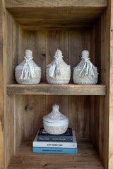 Decorative baskets on a wooden shelf with books underneath