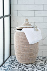 Wicker laundry basket with a white towel on a tiled bathroom floor