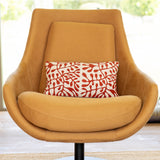 Orange armchair with a red and white patterned pillow in a bright room.