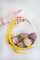 Hand holding a decorative basket with colorful Easter eggs on a white background