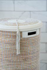 Close-up of flat-lidded white handwoven basket with leather trim handle and tassel