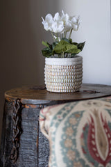 White handwoven open basket with white leather trim styled on a wooden side table with white flowers