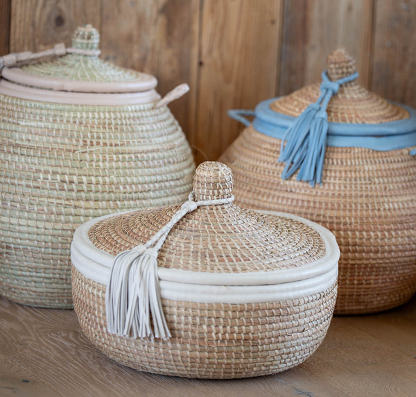 Three woven baskets with lids on a wooden surface