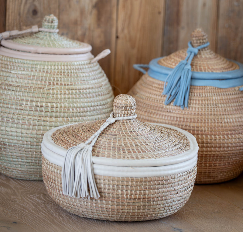 Three woven baskets with lids on a wooden surface