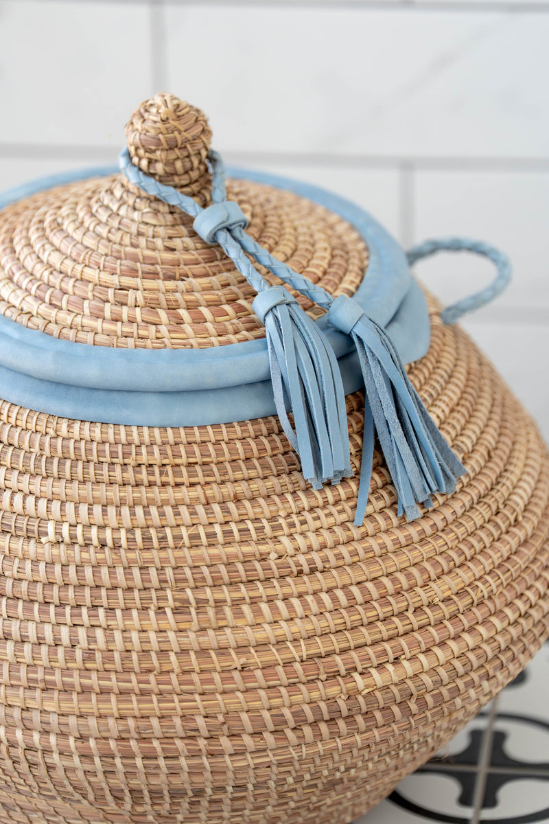 Woven basket with a lid and blue accents on a tiled floor