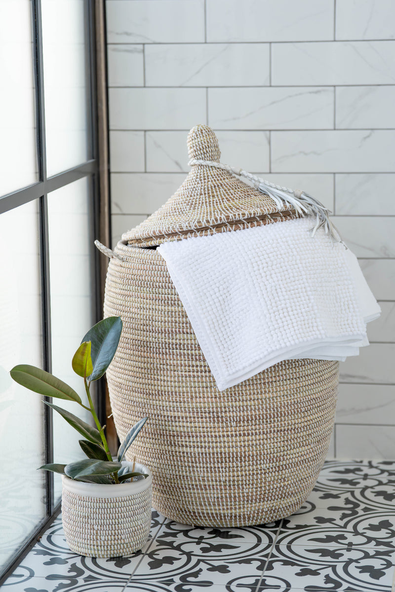 Wicker laundry basket with a white towel on a tiled floor