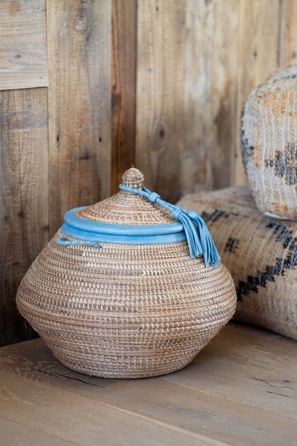 Woven basket with a blue ribbon on a wooden surface