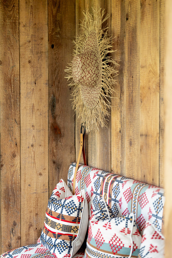 Decorative broom with a decorative pillow against a wooden wall