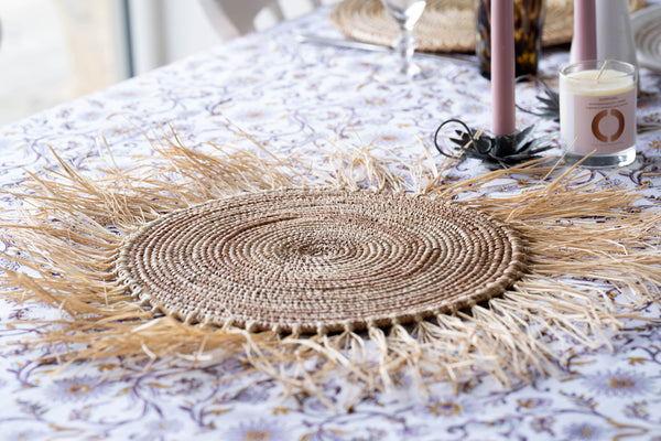 Woven placemat on a table with candles and decor