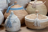 Woven baskets with lids and tassels on a wooden surface