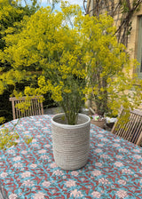 Handwoven Senegalese basket vase styled with yellow flowers outdoors