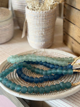 Set of blue beaded bracelets on a woven mat with blurred background