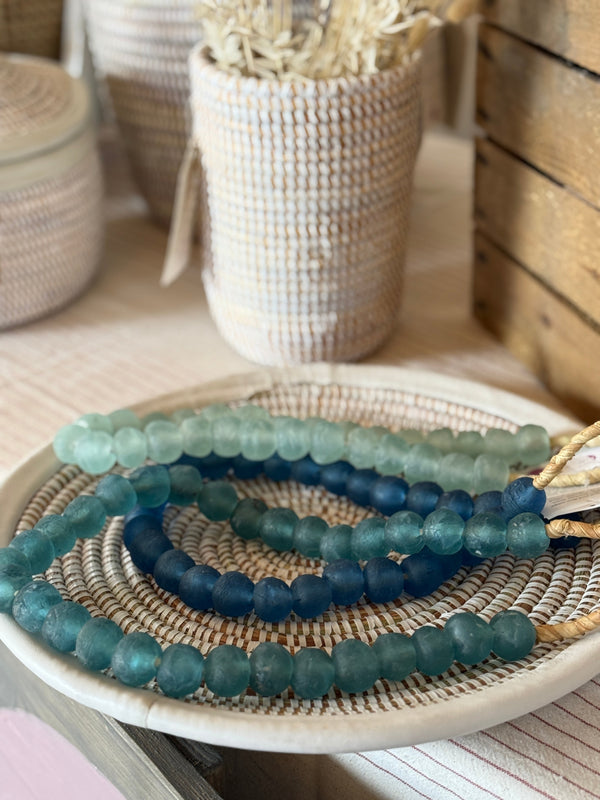 Set of blue beaded bracelets on a woven mat with blurred background