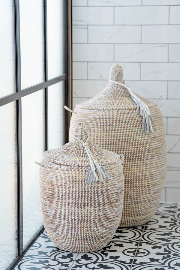 Two woven baskets with lids on a tiled floor.