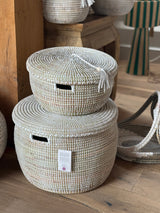 White handwoven lidded storage baskets with tassel stacked together on floor
