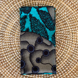 A striped napkin with blue, turquoise, and black geometric patterns, laid flat on a woven background.